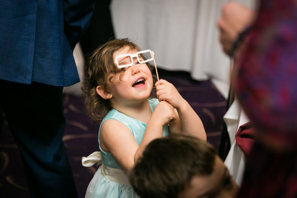 Little girl playing with photo booth prop at a Glen Terrace wedding
