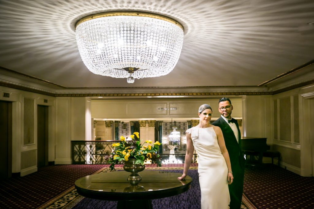 Couple standing under chandelier in Roosevelt Hotel for a NYC wedding destination guide