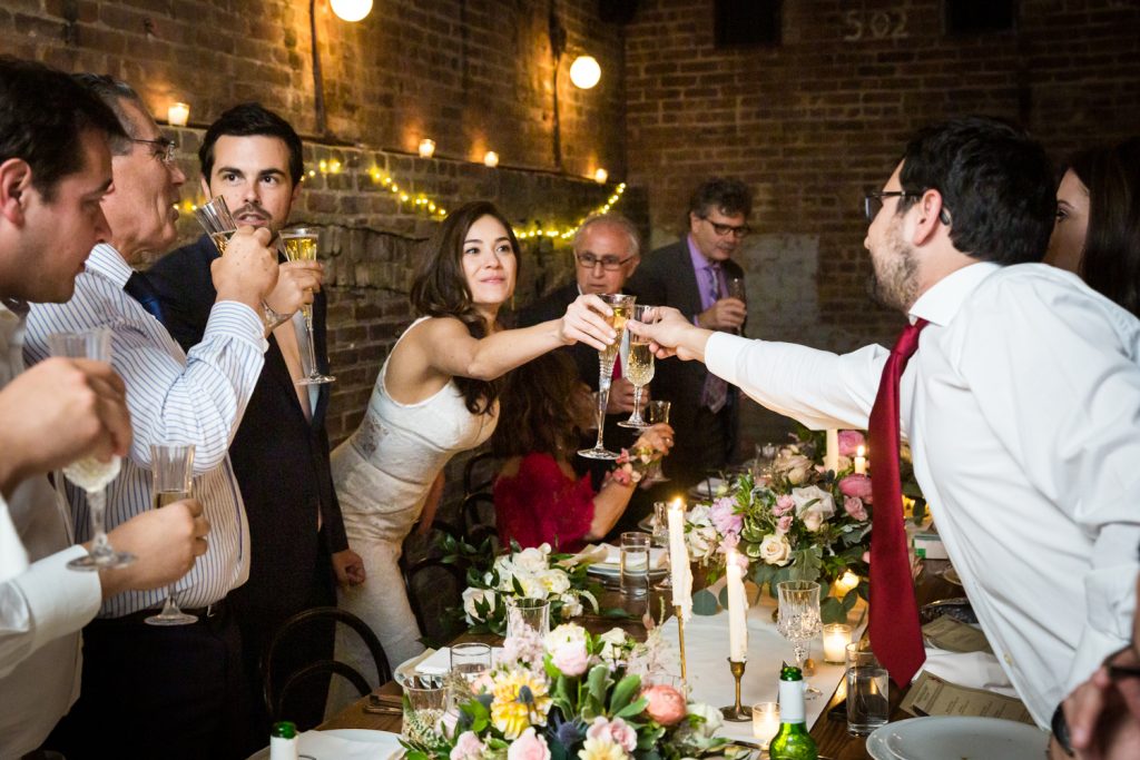 Bride toasting champagne glass with guest across table