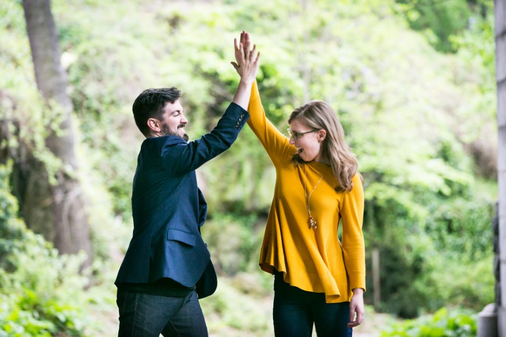 High-fiving couple at a Fort Tryon Park engagement portrait