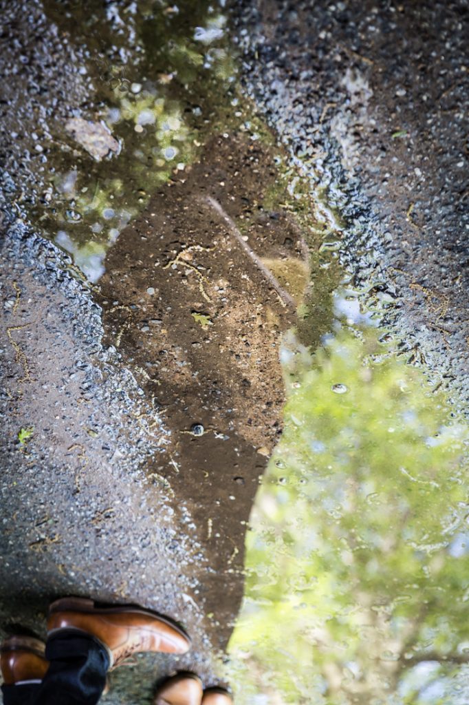 Couple reflected in water puddle at a Fort Tryon Park engagement portrait