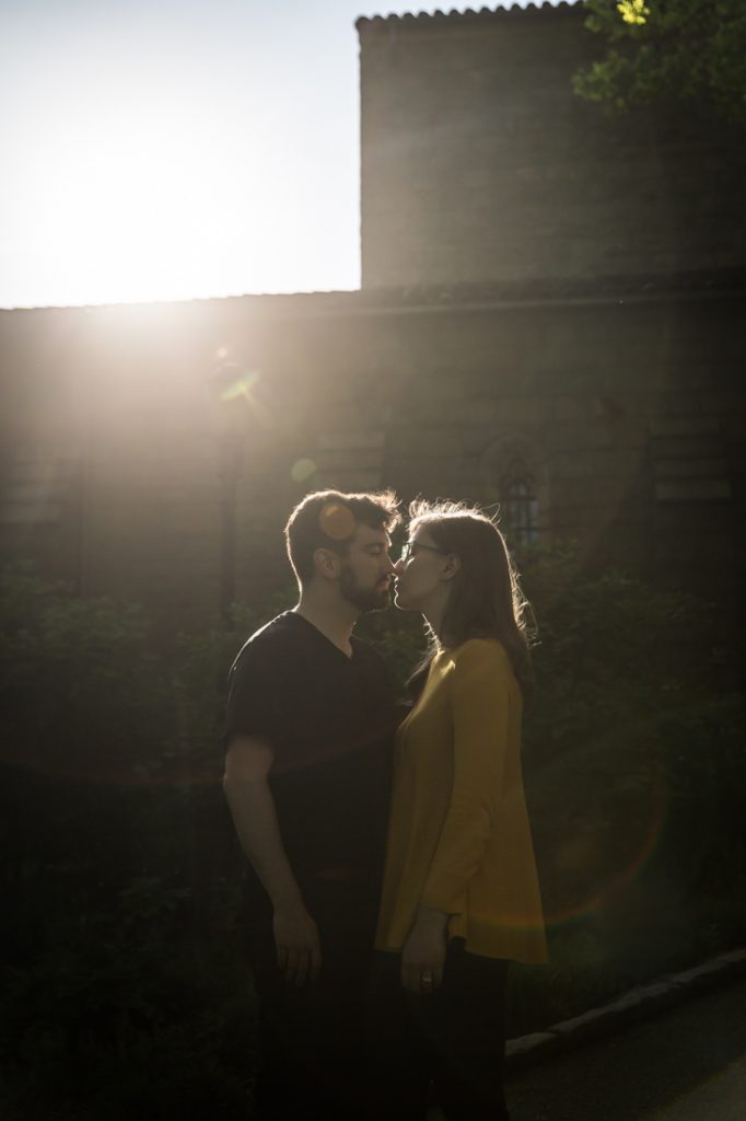 Kissing couple with sun flare at a Fort Tryon Park engagement portrait