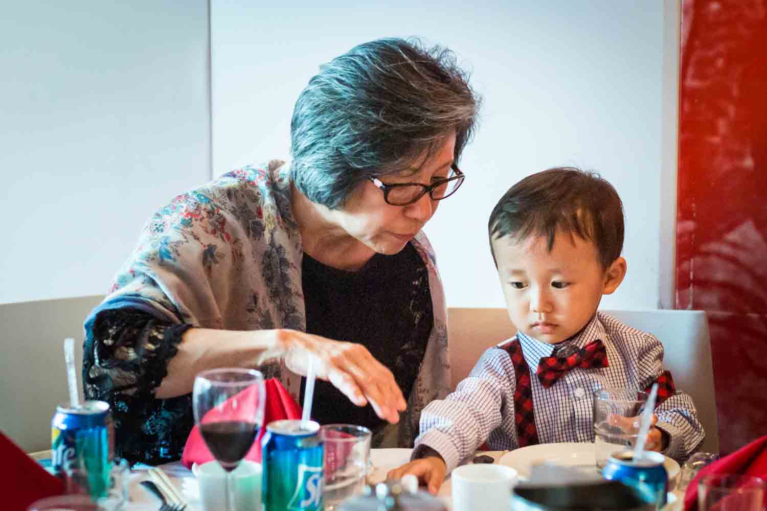 Grandmother helping little boy at a Chinatown rehearsal dinner