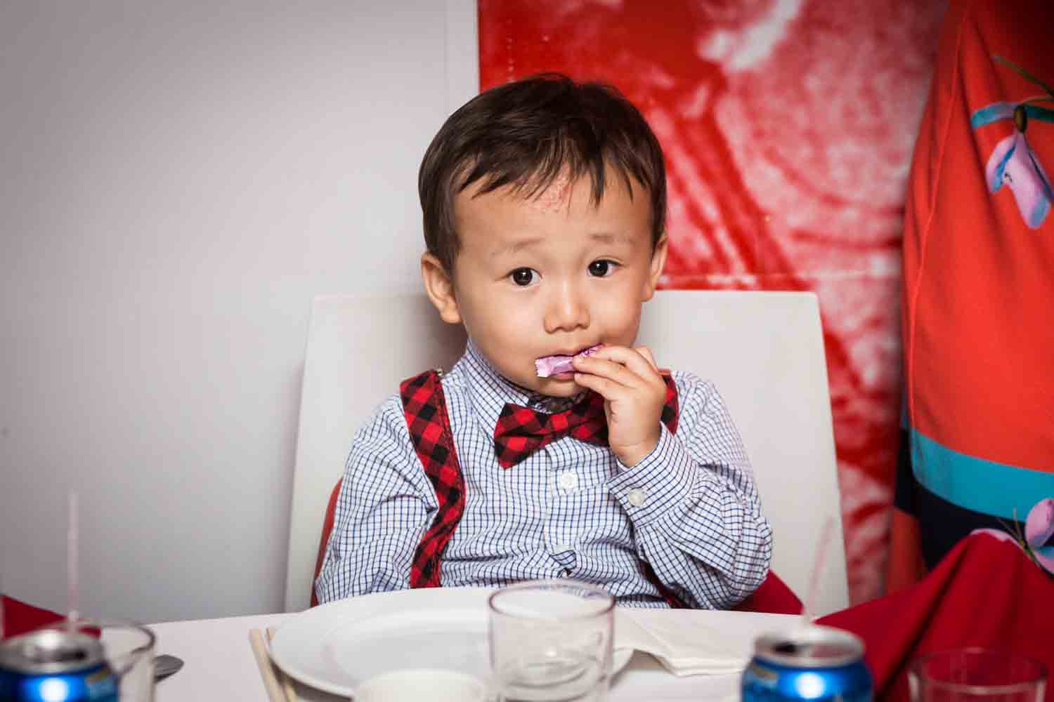 Little boy wearing bow tie and eating at a Chinatown rehearsal dinner