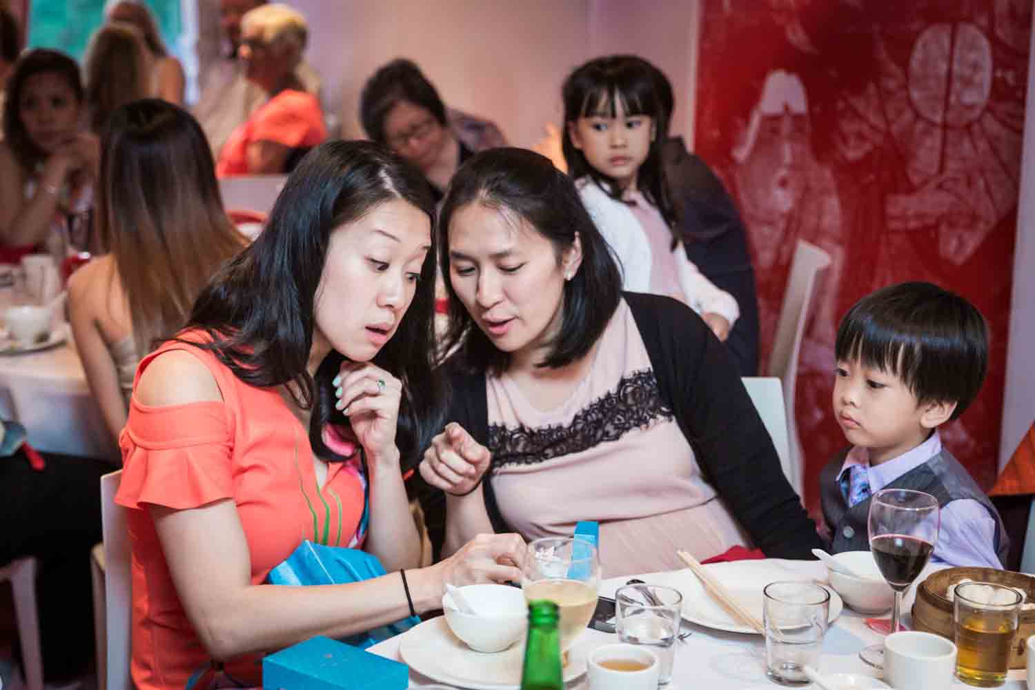 Bride and woman looking at cell phone at a Chinatown rehearsal dinner