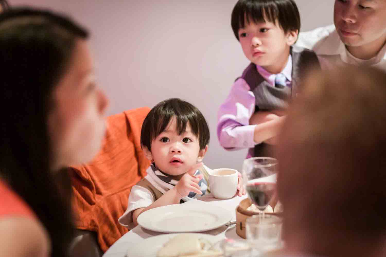 Two little boys watching woman at table