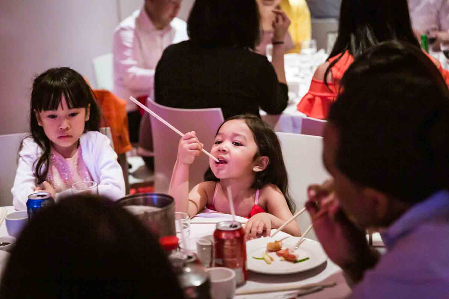 Little girl eating with chopsticks at a Chinatown rehearsal dinner