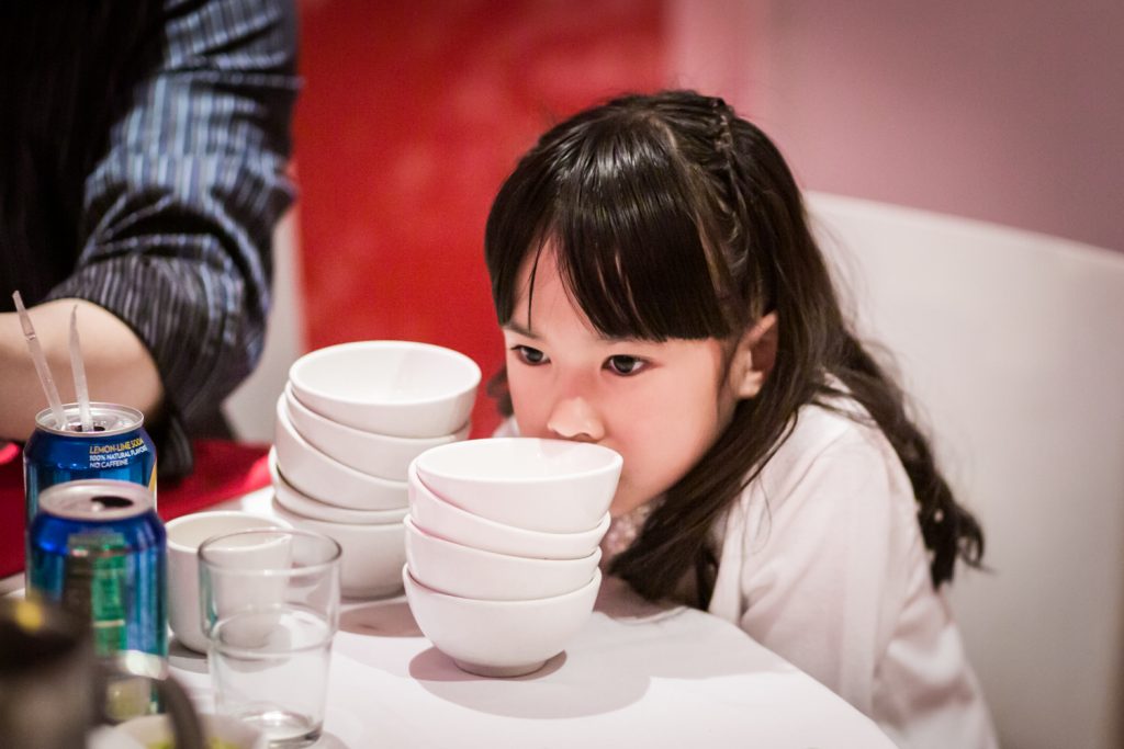 Little girl licking bowls at a Chinatown rehearsal dinner