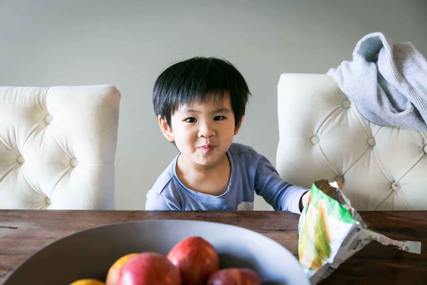 Little boy at table between two white chairs during a day in the life photography session