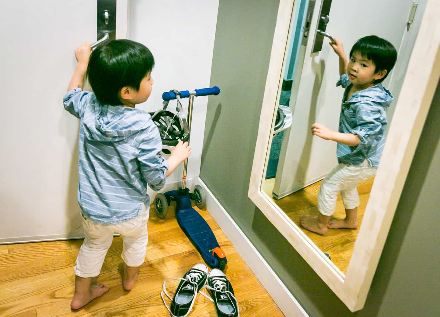 Little boy opening door and reflected in mirror