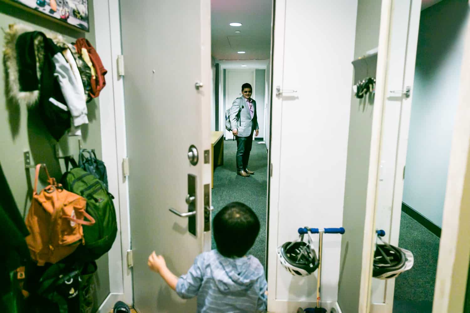Little boy opening door to see father in hallway