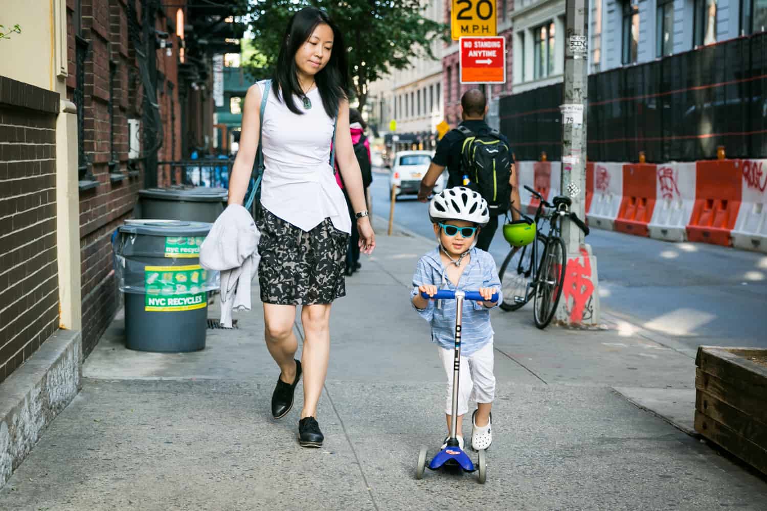Mother following little boy on scooter wearing helmet