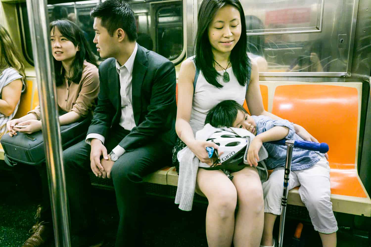 Little boy laying head in lap of mother on subway train