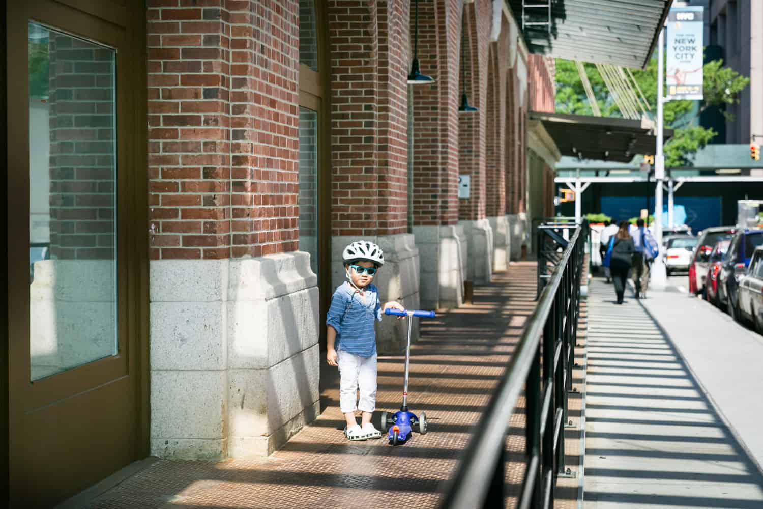 Little boy waiting with scooter for mother on sidewalk