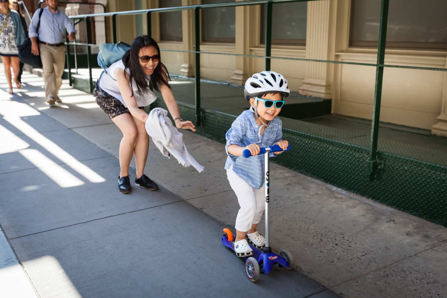 Mother pushing little boy on scooter