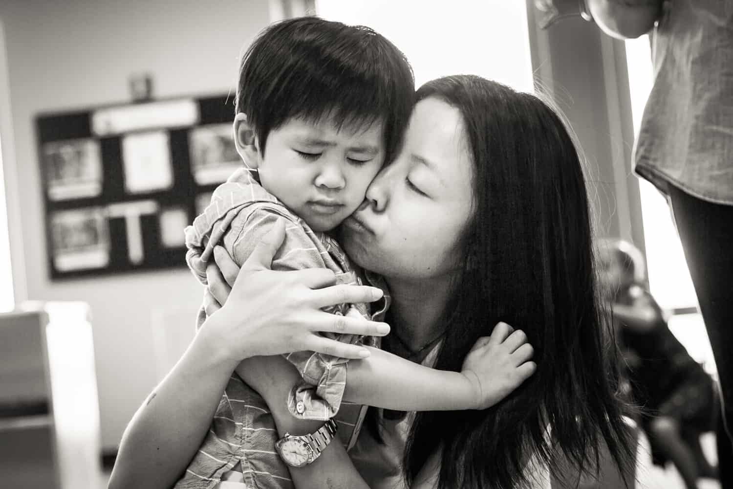 Black and white photo of mother comforting crying little boy
