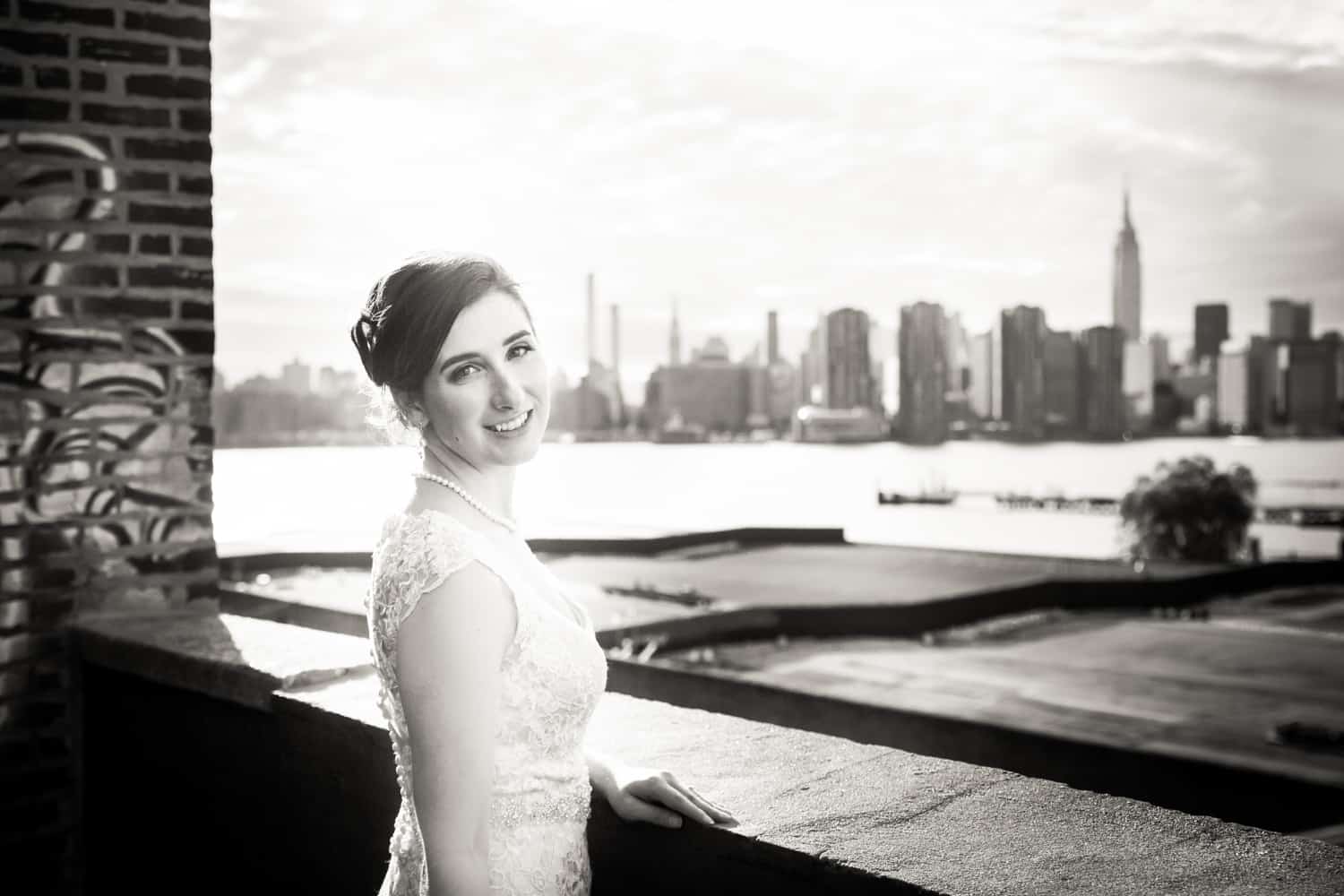 Black and white photo of bride on roof with view of NYC skyline