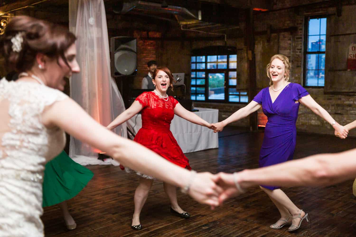 Bride and bridesmaids dancing in circle at a Greenpoint Loft wedding