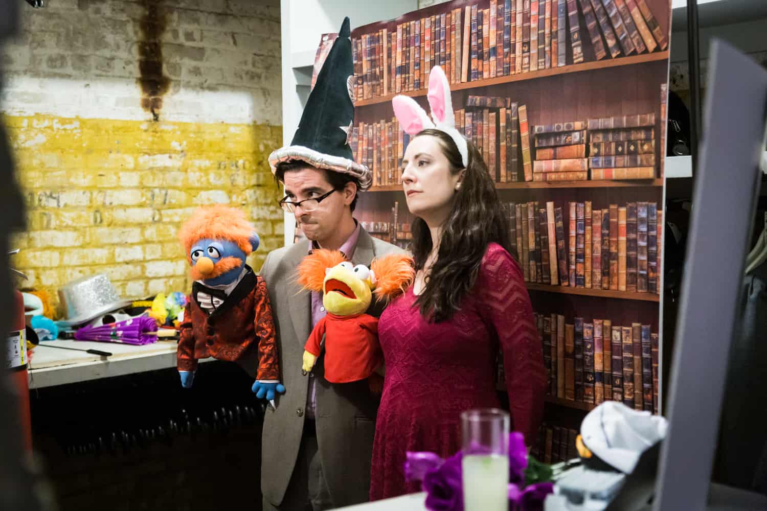 Couple dressed in bunny ears and wizard hat and holding puppets at a DIY photo booth