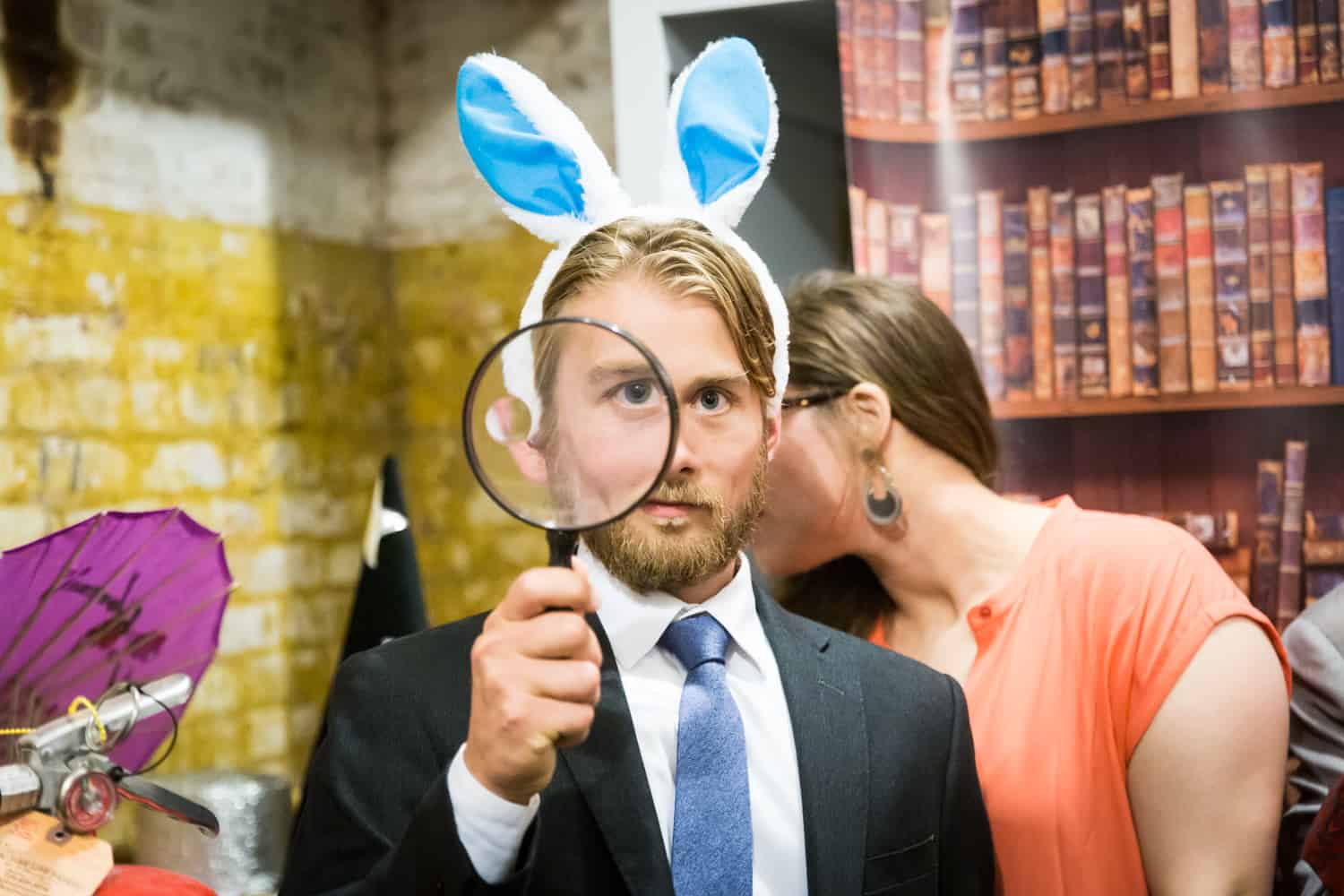 Man wearing bunny ears and holding a magnifying glass in a DIY photobooth