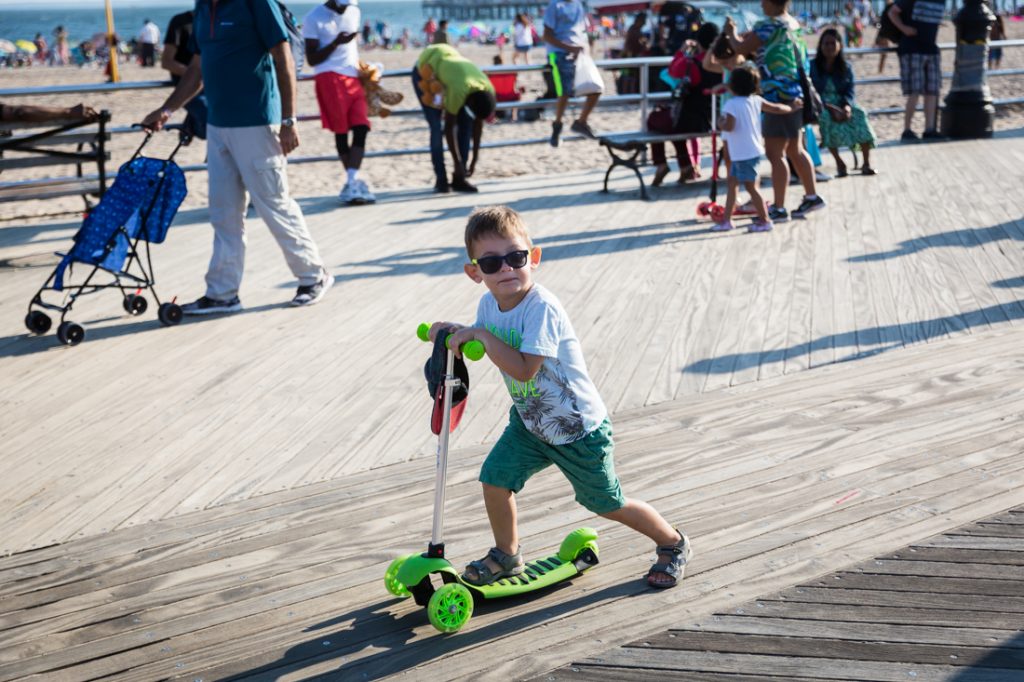 Kid on razor scooter on the Coney Island boardwalk