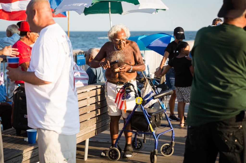 Old man with walker playing music on the Coney Island pier