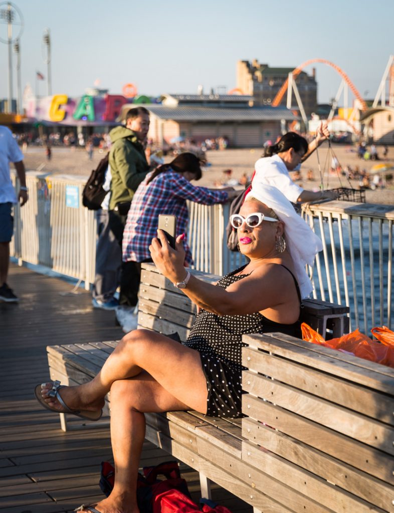 Woman with white turban talking into her phone on the Coney Island pier