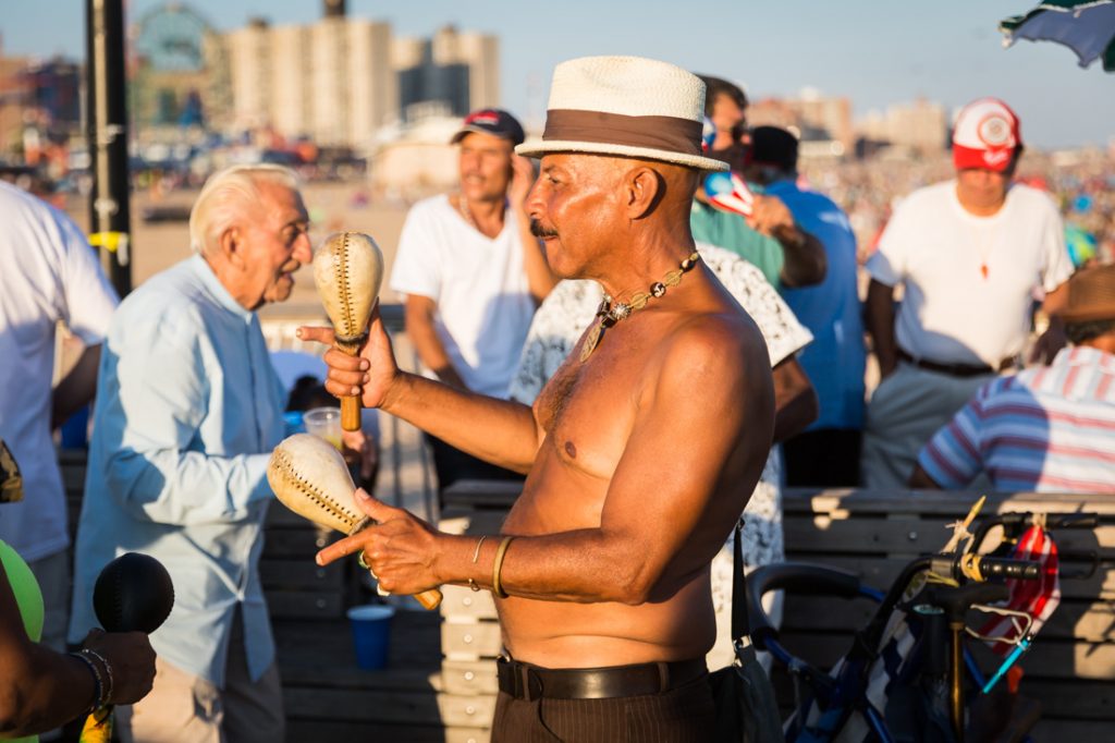 Shirtless man playing maracas on the Coney Island pier