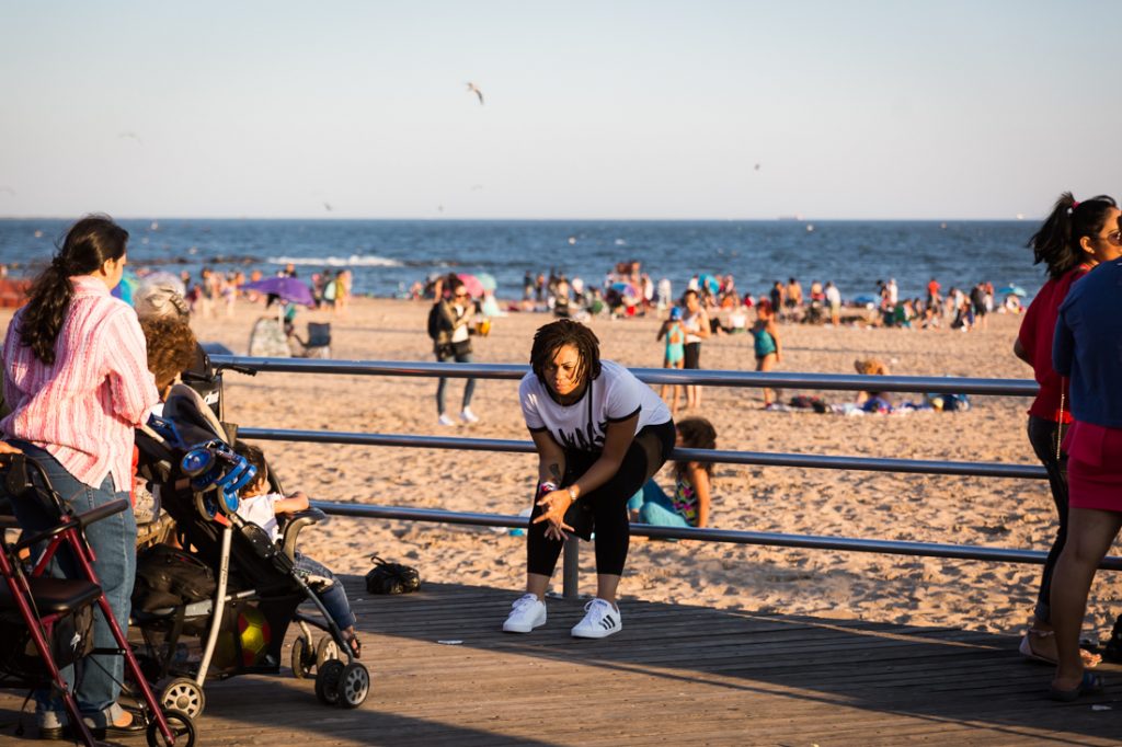 Woman sitting on the Coney Island boardwalk railing