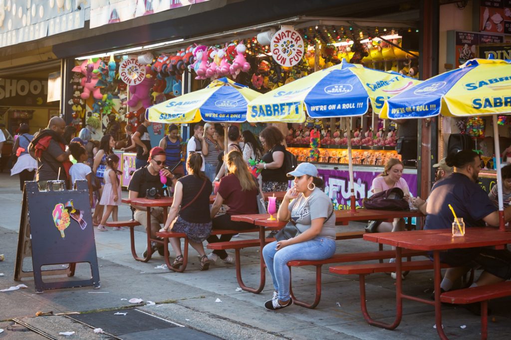 Woman sitting in front of carnival games at Coney Island