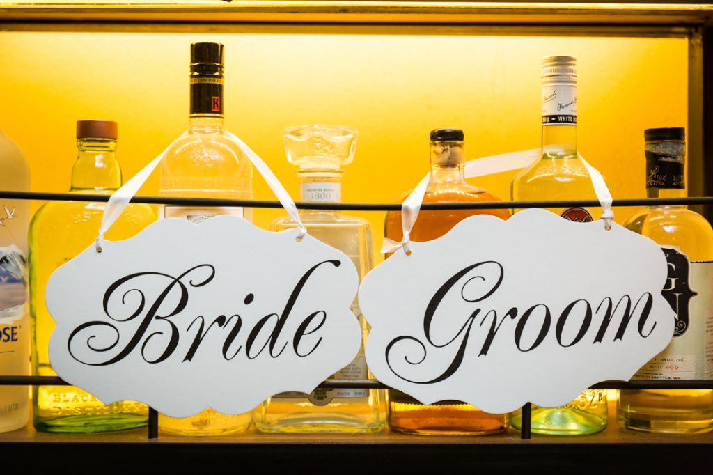 Bride and groom signs at a rehearsal dinner for an article on details your wedding photographer needs to know