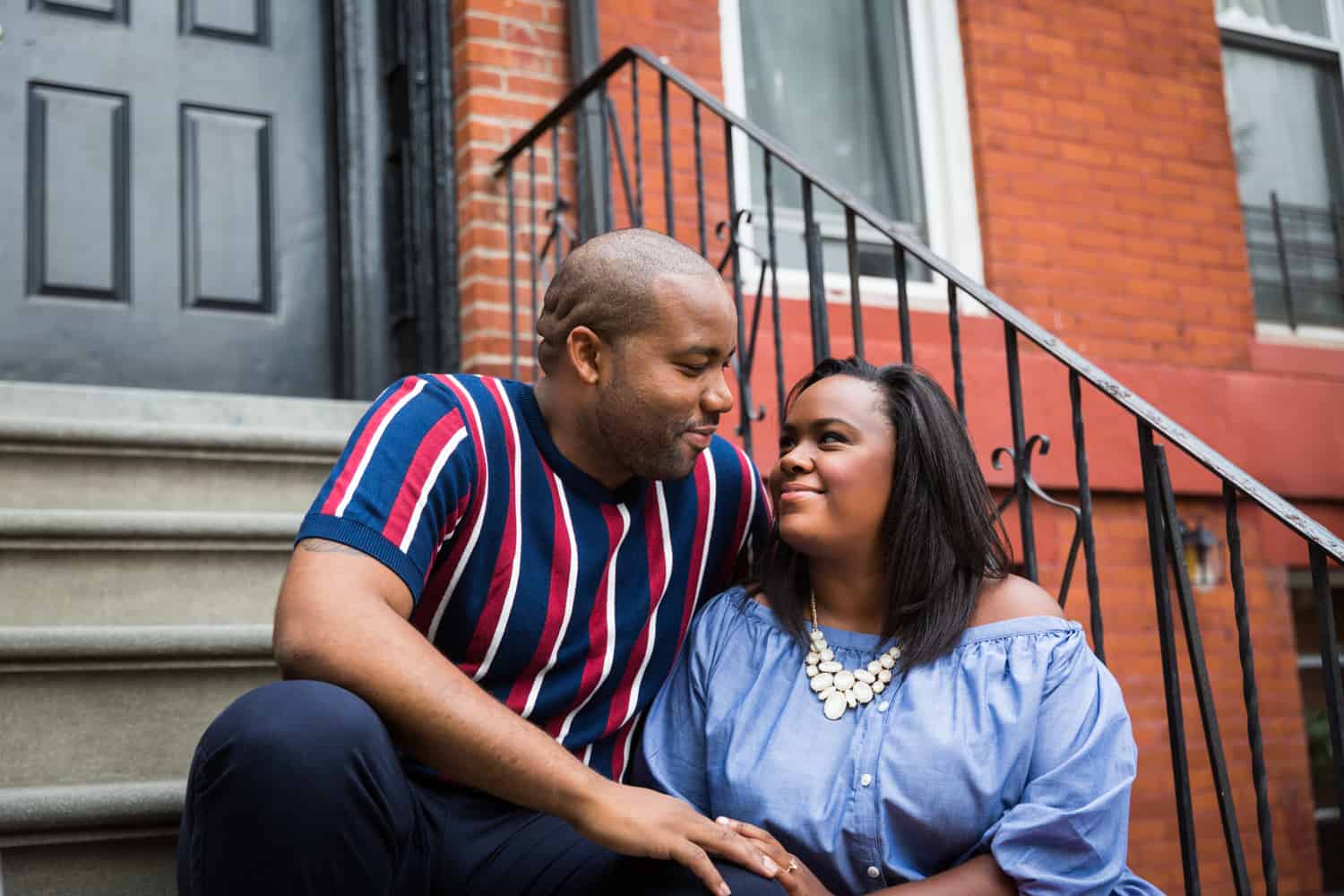 African American couple sitting on stairs in front of apartment building for an article on creative engagement photo shoot ideas