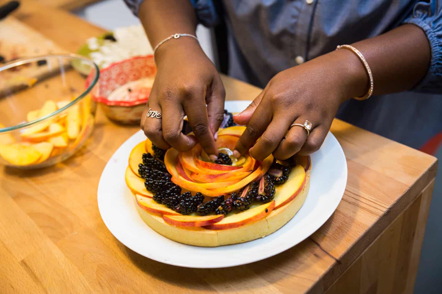 African American woman's hands arranging fruit tart 