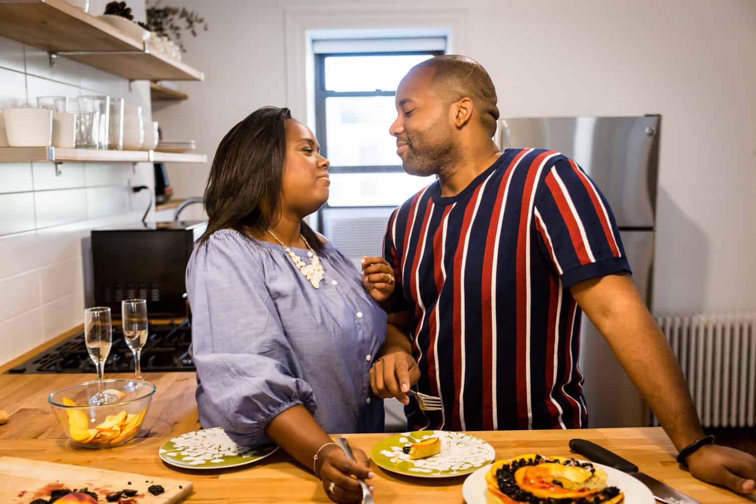African American couple eating fruit tart in kitchen for an article on creative engagement photo shoot ideas