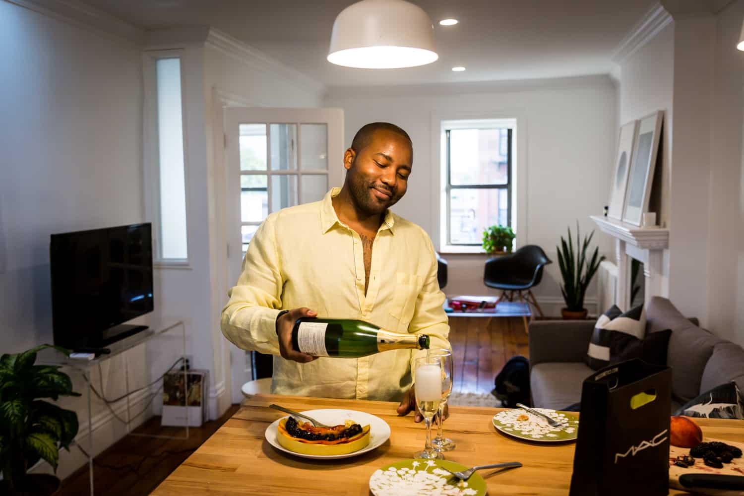 African American man pouring bottle of champagne for an article on creative engagement photo shoot ideas