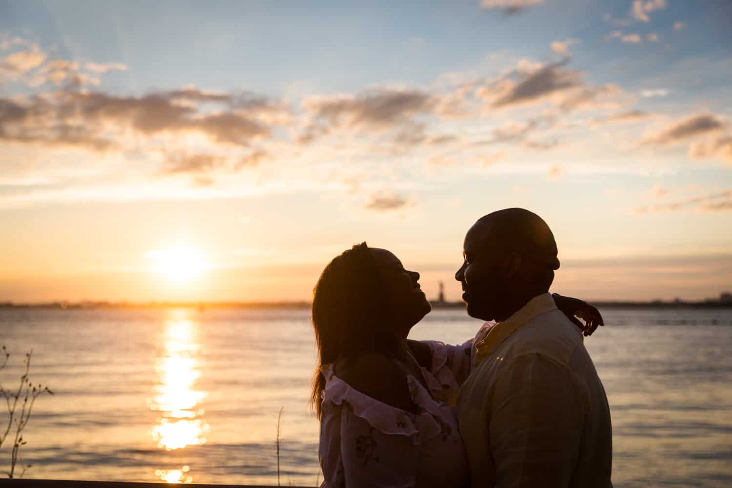 Backlit photo of couple in front of NYC waterfront at sunset
