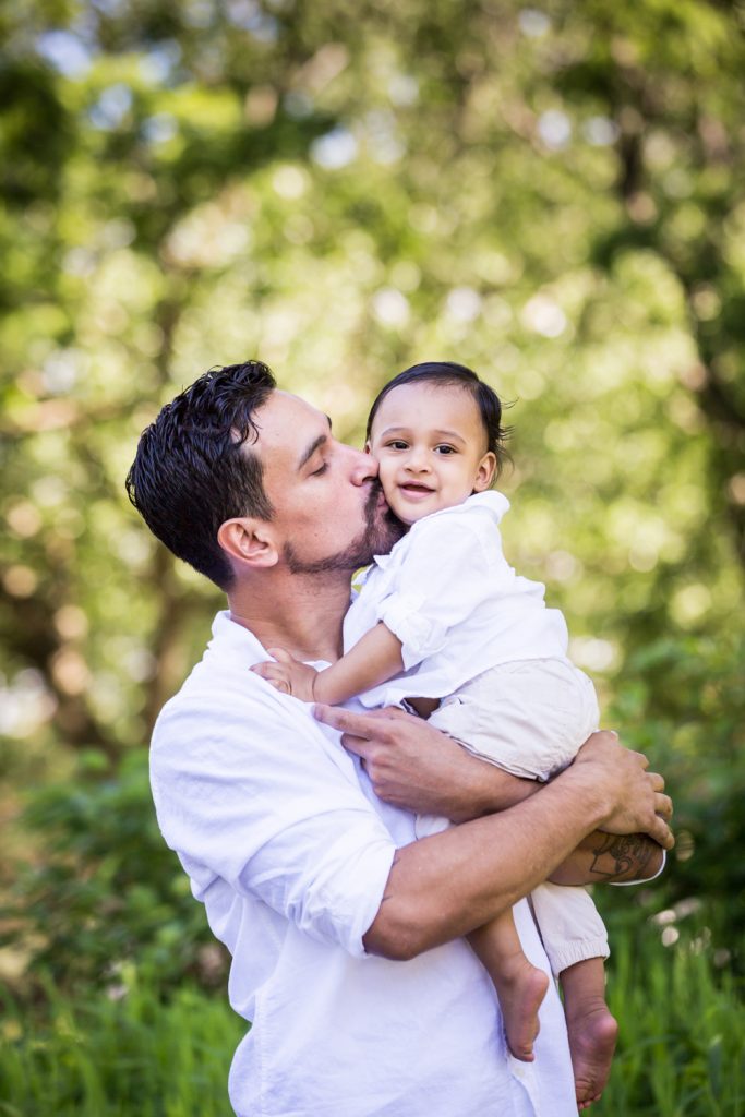 Father kissing little son on cheek in Forest Park