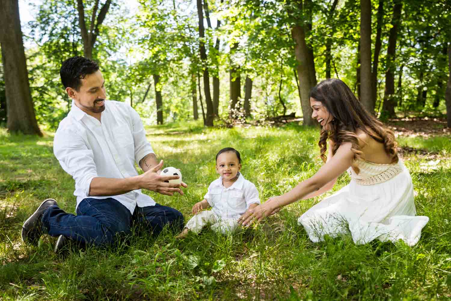 Forest Hills family portrait of parents playing in grass with son