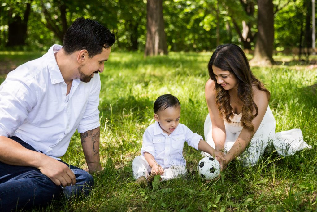 Parents playing in grass with son and soccer ball