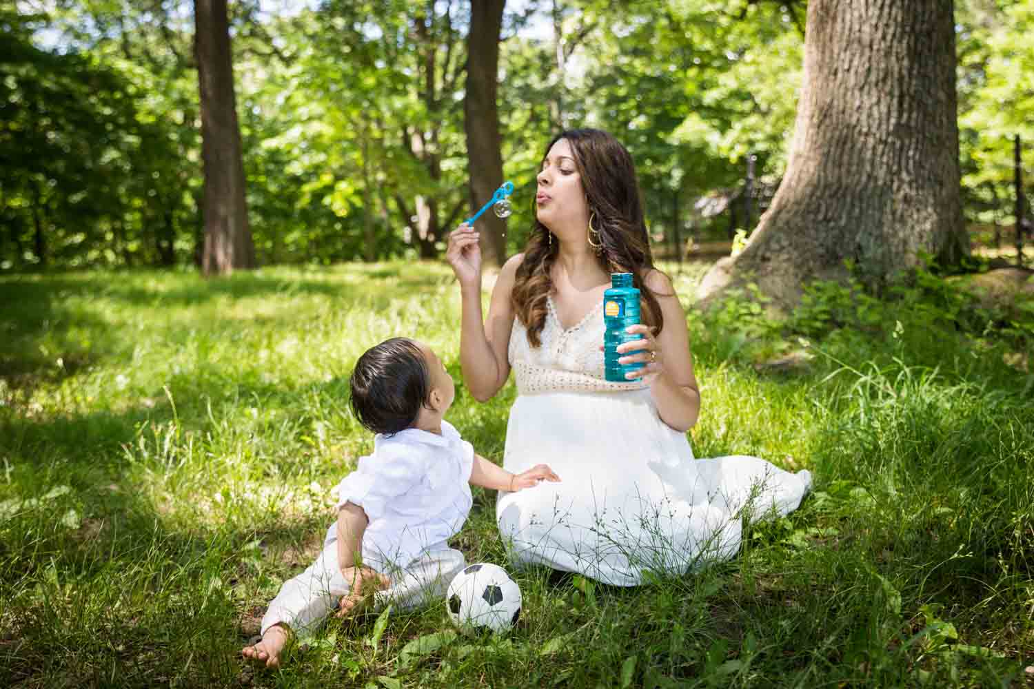 Mother blowing bubbles with son in grass
