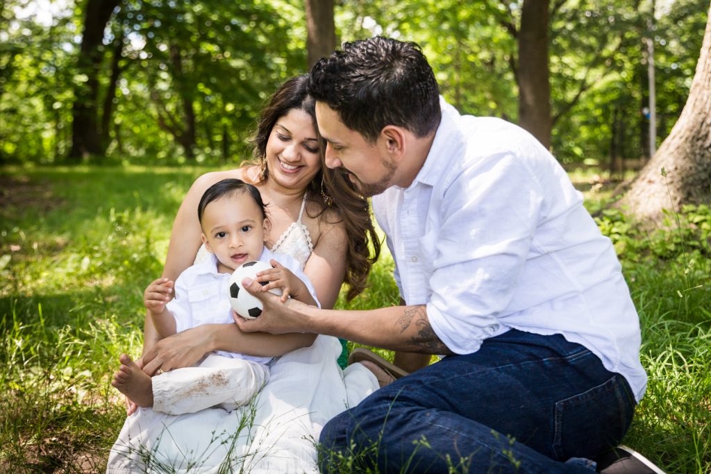 Forest Hills family portrait of parents playing with baby in the grass