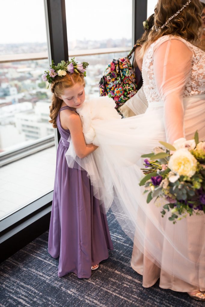 Flower girl holding bride's dress for a 26 Bridge wedding