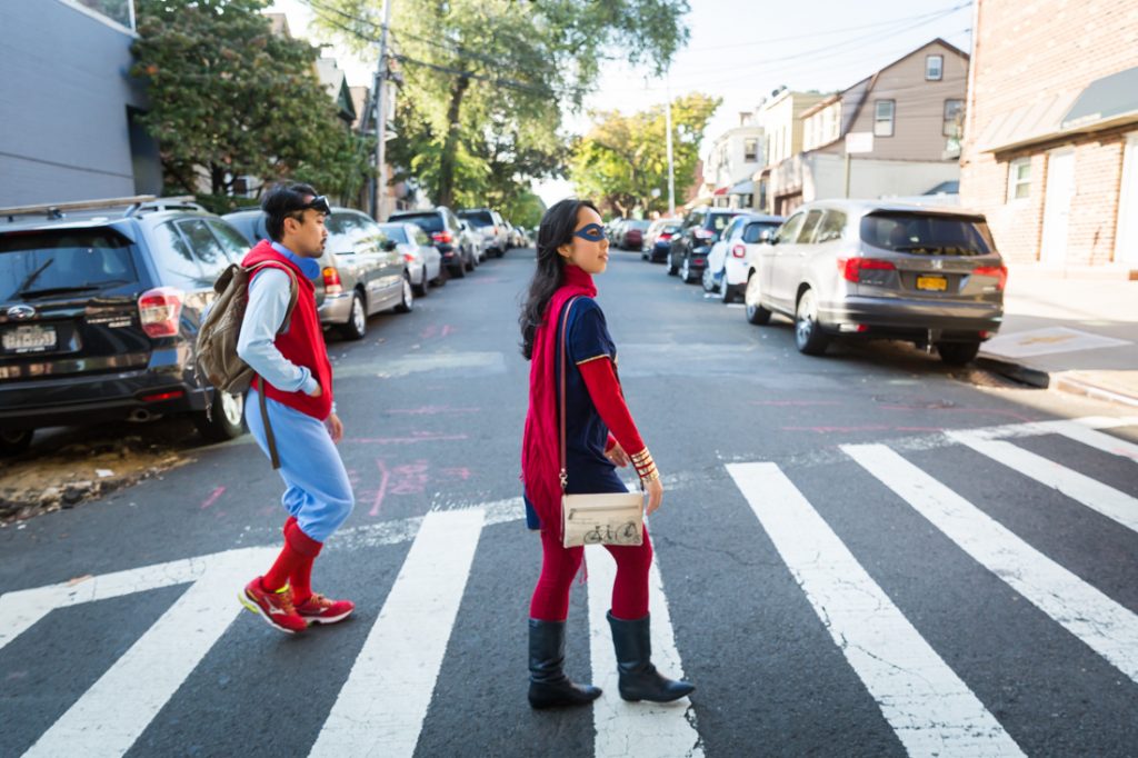 Couple walking in a crosswalk dressed as Spiderman and Supergirl for a Comic Con engagement shoot