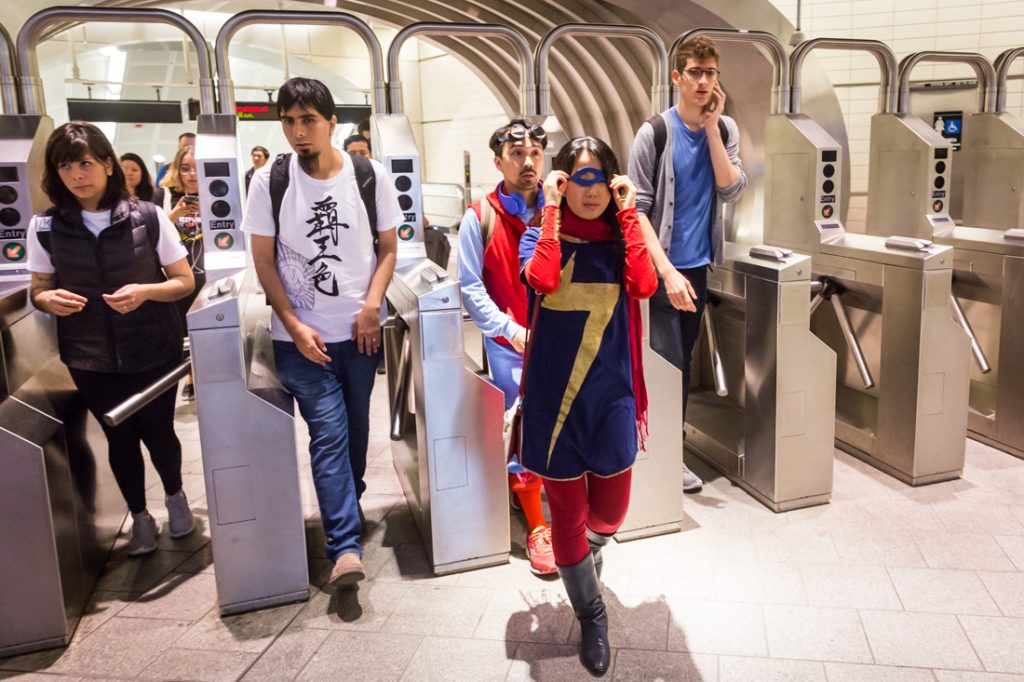 Couple commuting on the subway dressed as Spiderman and Supergirl for a Comic Con engagement shoot