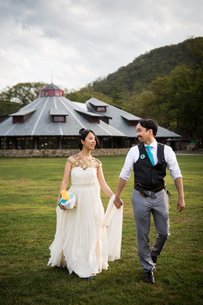 Bride and groom walking hand in hand away from carousel at a Bear Mountain Inn wedding