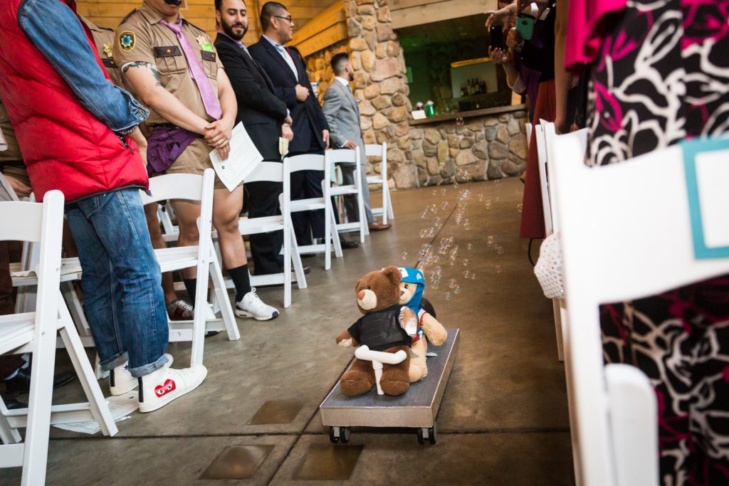 Two teddy bears on a cart moving down aisle with bubbles blowing at a Bear Mountain Inn wedding