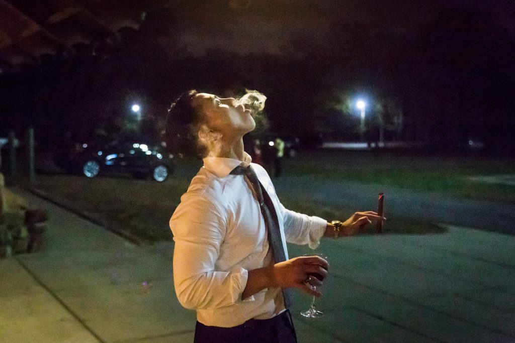 Male guest smoking cigar and blowing smoke at a Bear Mountain Inn wedding