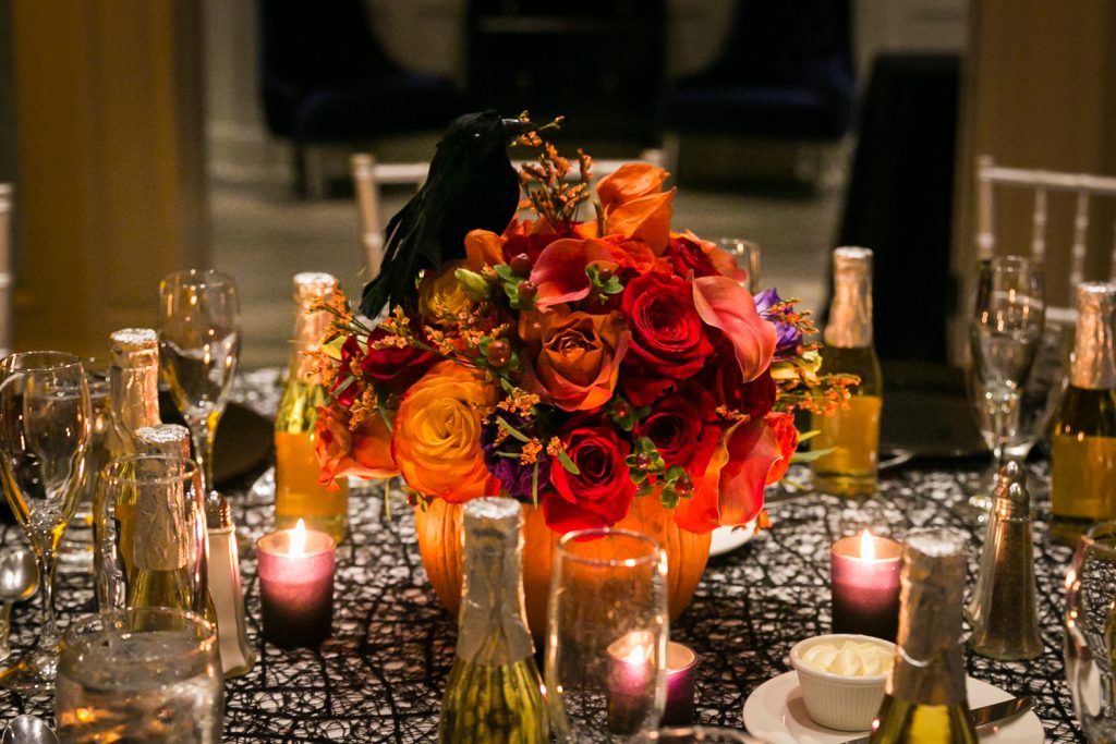 Table setting with orange flower centerpieces and candles for an article on how to plan a Halloween wedding