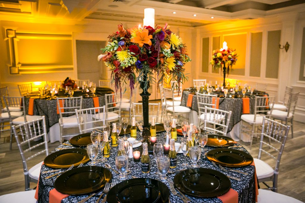 Table setting with flower centerpieces and candles for an article on how to plan a Halloween wedding