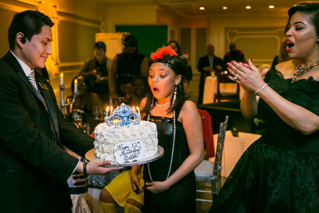 Young girl blowing out candles at a Halloween-themed wedding reception